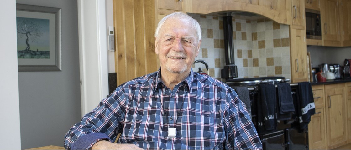 Smiling older man wearing fall detector pendant